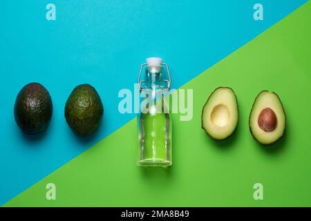 Frische Avocados auf blauem und grünem Hintergrund. Avocadoöl in einer Flasche. Stockfoto
