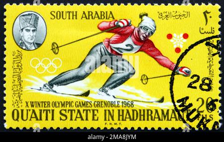 SÜDJEMEN - CIRCA 1967: Ein im südjemenitischen Staat Quaiti in Hadhramaut gedruckter Stempel zeigt Abfahrtsski, Olympische Winterspiele 1968, ca. 1967 Stockfoto