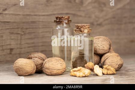 Walnussöl-Stillleben. Glasflaschennussöl auf rustikalem Holztisch Stockfoto