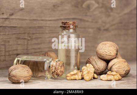 Walnussöl-Stillleben. Glasflaschennussöl auf rustikalem Holztisch Stockfoto