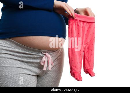 Nahaufnahme einer schwangeren Frau mit pinkfarbenen Babyhosen und auf weißem Hintergrund isolierten Socken als Kinderbekleidungskonzept Stockfoto