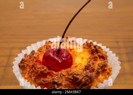 Goiânia, Goias, Brasilien – 18. Januar 2023: Detail eines Bombocados, eines typischen brasilianischen Süßes, gebacken in einer Papierform, mit einer Kirsche oben drauf. Stockfoto