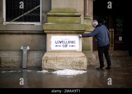 Eine Person sieht sich ein Schild mit dem Aufdruck „Powered by Levelling Up“ an, das kürzlich von Premierminister Rishi Sunak und Kanzler Jeremy Hunt an der Accrington Market Hall in Lancashire angebracht wurde. Herr Sunak hat seine Entschlossenheit bekräftigt, sich zu verbessern, da die Regierung £2 Milliarden Euro für mehr als 100 Projekte im Vereinigten Königreich angekündigt hat. . Foto: Donnerstag, 19. Januar 2023. Stockfoto