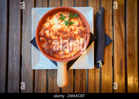 Nahaufnahme einer frisch gebackenen Lasagne in einem runden Topf. Stockfoto