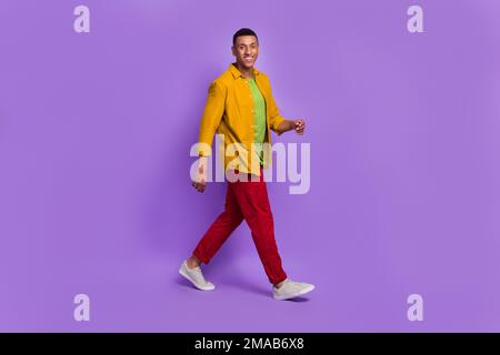 Das volle Profil Porträt eines zufriedenen, freundlichen jungen Mannes, der ein Lächeln strahlt und isoliert auf lila Hintergrund läuft Stockfoto