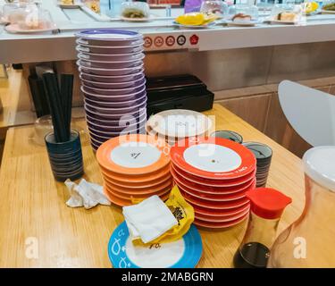 Putrajaya, Malaysia - 20. Juli 2022 Leere schmutzige Teller nach Sushi gestapelt nach den Farben in Sushi Kings, Malaysia. Stockfoto