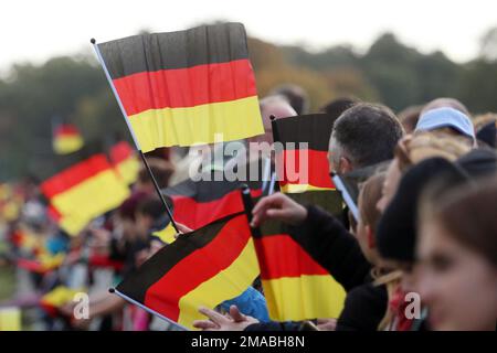 03.10.2022, Deutschland, Brandenburg, Hoppegarten - Menschen, die am Tag der deutschen Einheit die Nationalflaggen schwingen. 00S221003D936CAROEX.JPG [MODELLVERSION: NEIN, MODELLVERSION Stockfoto
