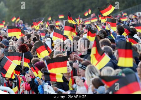 03.10.2022, Deutschland, Brandenburg, Hoppegarten - Menschen winken am Tag der deutschen Einheit Nationalflaggen. 00S221003D942CAROEX.JPG [MODELLVERSION: NEIN, MODELLVERSION Stockfoto