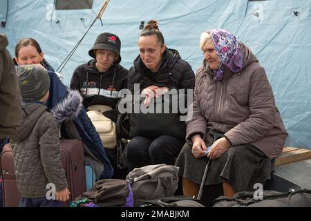 15.04.2022, Ukraine, Oblast, Lemberg - Ukrainische Kriegsflüchtlinge versammeln sich vor dem Hauptbahnhof in Lemberg. Eine Flüchtlingsfamilie mit Gepäck sitzt Stockfoto