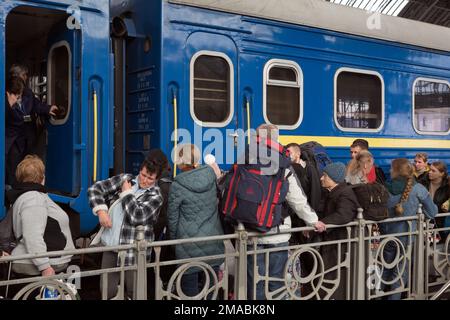 15.04.2022, Ukraine, Oblast, Lemberg - Ukrainische Kriegsflüchtlinge mit Rucksäcken stehen auf dem Bahnsteig neben einem Zug im Hauptbahnhof von Lemberg. Achtung: Nur Stockfoto