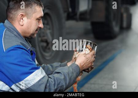 Automechaniker repariert Lkw. Professionelle Reparatur und Diagnose von Frachttraktoren und -Ausrüstung. Der Mechaniker in der Werkstatt berücksichtigt Ersatzteile. Stockfoto