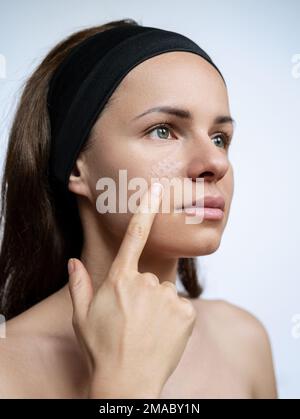 Junge Erwachsene Frau, die ein Kinesio-Gesichtsband auf ihr Gesicht aufklebt, Falten im Gesicht kleben. Stockfoto