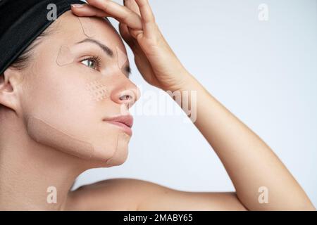 Erwachsene Frau kleben Kinesio-Bänder auf ihr Gesicht, Falten kleben. Stockfoto