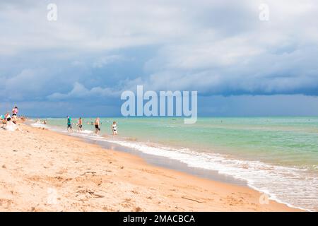 Sandstrand Schwarzes Meer und dunkler Himmel an einem Sommertag vor dem Regen, Touristen sonnen und schwimmen. Russland, Region Krasnodar-10,08,2021 Stockfoto