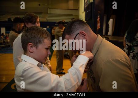 MARINESTÜTZPUNKT KITSAP-BREMERTON, WASHINGTON (25. Mai 2022) – Senior Chief Electronics Technician (Nuclear) Ryan Williams, am Flugzeugträger der Nimitz-Klasse USS Theodore Roosevelt (CVN 71) befestigt, wird von seinem Sohn während einer beeindruckenden Zeremonie im Auditorium der Naval Base Kitsap, Bremerton, Washington, festgehalten., 25. Mai 2022. Theodore Roosevelt ist in einer geplanten Andockphase in der Puget Sound Naval Shipyard and Intermediate Maintenance Facility, wo das Schiff planmäßige Wartungs- und Modernisierungsmaßnahmen erhält. Stockfoto