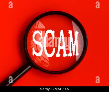 Betrügertext auf rotem Umschlag mit Lupe. Betrugs- und Betrugskonzept Stockfoto