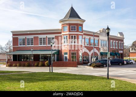 MATTHEWS, NC, USA-15. JANUAR 2023: Elegantes Mehrzweck-Geschäftsgebäude am Bahnhof Matthews gegenüber dem Rathaus. Sonniger, blauer Himmel. Stockfoto