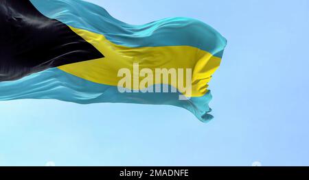 Aus nächster Nähe sehen Sie die Nationalflagge der Bahamas, die im Wind winkt. Schwarzes Dreieck auf dem Hebezeug, Aquamarin-Gold-Aquamarin-Horizontalbänder. Geriffelter Stoff. Stockfoto