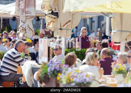 Estland, Tallinn, Touristen und Einheimische genießen einen entspannenden Drink auf dem Marktplatz. Stockfoto