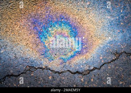 Mehrfarbiges Ölteppich auf Asphaltstraße. Das Konzept der Umweltverschmutzung, der Ölverschmutzung und der Umweltprobleme. Stockfoto