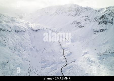 Schneebedeckte Berggipfel im Winter an einem sonnigen Tag mit Wolken im Fluela Pass, Davos, Schweiz. Stockfoto