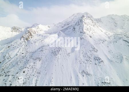 Schneebedeckte Berggipfel im Winter an einem sonnigen Tag mit Wolken im Fluela Pass, Davos, Schweiz. Stockfoto