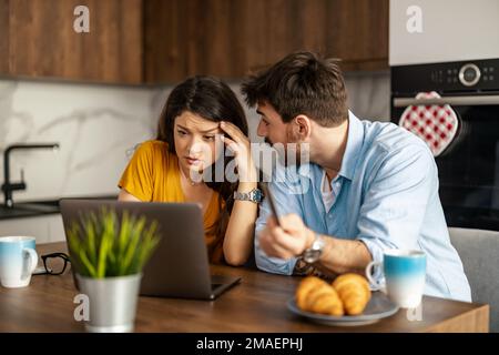 Unglückliches, gestresstes und aufgebrachtes Paar, das Rechnungen mit einem Laptop bezahlt.Finanz-, Konkurs- und Finanzprobleme Konzept. Stockfoto