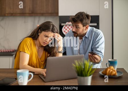 Unglückliches, gestresstes und aufgebrachtes Paar, das Rechnungen mit einem Laptop bezahlt.Finanz-, Konkurs- und Finanzprobleme Konzept. Stockfoto