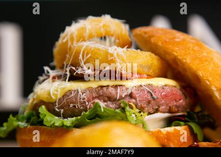 Amerikanischer Burger mit Käse und Zwiebelringen auf der Oberseite. Stockfoto