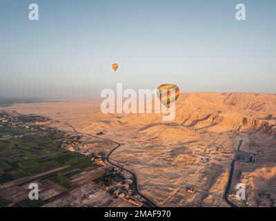 Luftaufnahme der landwirtschaftlichen Felder, der Wüste Luxor und Ballons von einem Heißluftballon bei Sonnenaufgang. Stockfoto