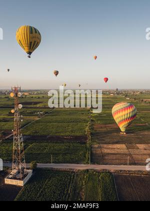 Luftaufnahme der landwirtschaftlichen Felder und Luxor und Ballons von einem Heißluftballon bei Sonnenaufgang. Stockfoto
