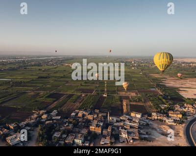 Luftaufnahme der landwirtschaftlichen Felder und Luxor und Ballons von einem Heißluftballon bei Sonnenaufgang. Stockfoto