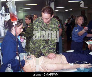 060428-N-0780W-001. [Complete] Scene Caption: Canadian Armed Forces (CAF) Corporal (CPL) Connie Scuncio (Zentrum), führt an einer Schaufensterpuppe eine Herz-Lungen-Wiederbelebung (CPR) durch, während einer Massenübung bei Verletzten, durchgeführt an Bord des US Navy (USN) Military Sealift Command (MSC) Mercy Class Hospital Ship, USNS COMFORT (T-AH 20) Wie USN Hospital Corpsman dritte Klasse (HM3) Mandy Gilley (links) zählt Herzkompressionen. Der KOMFORT und ihre Crew sind derzeit im Atlantik unterwegs nach Halifax, Neuschottland, um an einer internationalen Trainingsübung mit der kanadischen Armee teilzunehmen Stockfoto