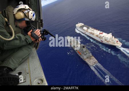 060516-N-6501M-029. [Complete] Scene Caption: US Navy (USN) Photographer's Mate Second Class (PH2) Gregory E. Badger verwendet einen digitalen Videorekorder, um Aktivitäten von seiner Luftplattform aus zu dokumentieren, von RAS-Operationen (Replenishment at Sea) zwischen dem US Navy (USN) Military Sealift Command (MSC), Henry J. Kaiser Class: Öler, USNS PECOS (T-AO197) und das USN MSC Hospital Ship, USNS MERCY (T-AH 19), während die Schiffe im Pazifischen Ozean während eines geplanten fünfmonatigen Einsatzes zur Bereitstellung von Hilfe und humanitärer Hilfe für die Pazifikinseln und Südostasien unterwegs sind.2006) P Stockfoto