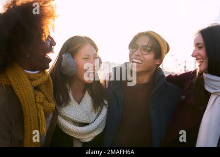 Eine Gruppe von vier multiethnischen Freunden, die im Winter im Freien abhängen. Stockfoto