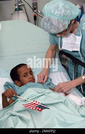 060705-N-3532C-001. [Complete] Szene Caption: US Navy (USN) Commander (CDR) Tanya Ponder verabreicht einem Jungen, der nach seiner Operation eine kleine amerikanische Flagge an Bord des US Navy (USN) Military Sealift Command (MSC) USNS MERCY (T-AH 19) hält, während des Besuchs für humanitäre und zivile Hilfe in Chittagong, Bangladesh (BGD), eine Betäubung. Die GNADE gilt einem geplanten Einsatz für fünf Monate in Südostasien. Die Mission wird in enger Abstimmung und Partnerschaft mit lokalen medizinischen Fachkräften und zivilen Freiwilligen des Projekts HOPE (Health Opportunities for People ever) durchgeführt Stockfoto