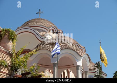 Blick auf das Kloster des Erzengels Michael in Griechenland, Thasos Island, mit leuchtend orangefarbenen Wänden und Dach, das Kloster wurde an der Klippe über dem Meer gebaut Stockfoto