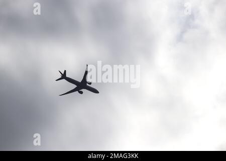 Flugzeugsilhouette auf dem Hintergrund des Sturmhimmels. Kommerzielles Flugzeug, das in dunklen Wolken abhebt, Turbulenzkonzept Stockfoto