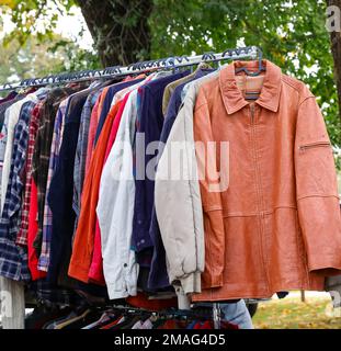 Alte gebrauchte Kleidung und neue Kleider im Stand auf dem Flohmarkt Stockfoto