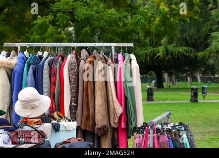 Alte gebrauchte Kleidung und neue Kleider im Stand auf dem Flohmarkt Stockfoto