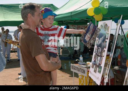 060903-N-6501M-002. [Complete] Scene Caption: Ein australischer Vater und Sohn sehen sich eine Anzeigetafel mit Fotos der USA an Navy Military Sealift Command Mercy Class Hospital Ship USNS MERCY (T-AH 19) auf See während eines von der NAPCAN Foundation gesponserten 'Fishing Fun Day', der am 3. September 2006 in der Stadt Darwin, Northern Territory, Australien, stattfindet. Die NAPCAN-Stiftung widmet sich der Prävention von Kindesmissbrauch und nutzt diese Familienveranstaltungen, um ihre Botschaft zu vermitteln. Im Hintergrund die USA Navy Show Band, mit der medizinischen Behandlungseinrichtung an Bord der GNADE, ist Stockfoto