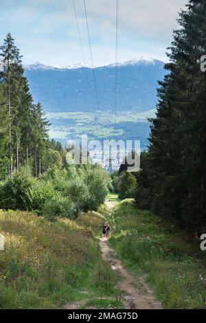 Wandern in Innsbruck, Sommerblick auf zwei junge Menschen, die auf dem Kreuzbrundlweg Trail - einer von mehreren Wanderwegen zur Nordkette in Innsbruck - spazieren Stockfoto