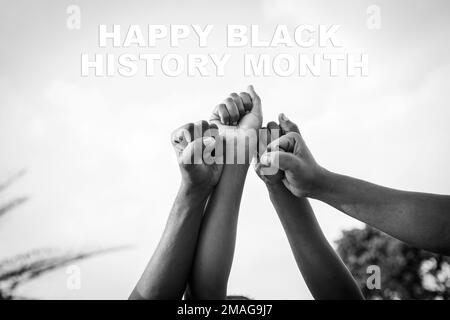 Vier Fäuste afrikanischer Menschen wurden mit den Worten "Happy Black History Month" in den Himmel gehoben, Schwarzweißfoto Stockfoto