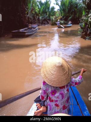 Vietnamesische Frau mit konischem Nón lá-Hut, die Sampan durch das Mekong-Delta, Einhorn-Insel, My Tho, Sozialistische Republik Vietnam paddelt Stockfoto