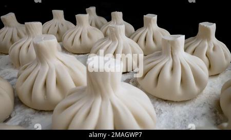 Georgianische Küche - Khinkali mit Fleisch. Ein Teller mit Khinkali in der Hand Nahaufnahme. Khinkali-Nahaufnahme. Stockfoto
