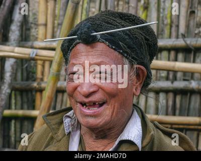 Ziro, Arunachal Pradesh, Indien - 02 19 2013 : Portrait des glücklichen alten Apatani-Stammesmanns mit traditionellem Stirnhaarbrötchen und Nadel mit schwarzer Mütze Stockfoto