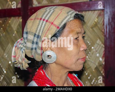 Raga, Arunachal Pradesh, Indien - 02 25 2009 : Profilporträt einer Nyishi-Stammesfrau mit Kopftuch und traditionellen Ohrringen und roten Halsketten Stockfoto