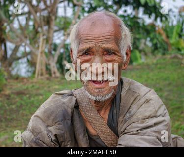 Mon, Nagaland, Indien - 03 02 2009 : Portrait des lächelnden alten Naga Konyak-Stammesjäger-Kriegers mit traditioneller Tätowierung im Gesicht auf dem Naturhintergrund Stockfoto