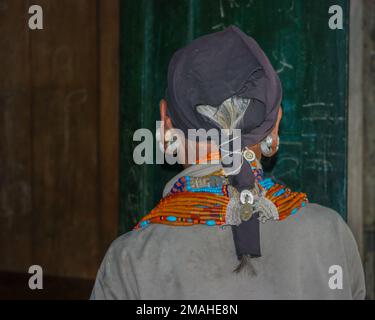 Mon, Nagaland, Indien - 03 03 2009 : Porträt der alten Frau des Naga Konyak-Stammes mit traditioneller Halskette und Ohrringen mit schwarzem Kopftuch Stockfoto