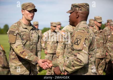 Army 1. LT. John Governn mit 2. Brigade Combat Team, 10. Mountain Division, schüttelt Colonel Damon Harris, 2. BCT Commander, während einer Preisverleihung im Sexton Field in Fort Drum, New York, 26. Mai 2022 die Hand. Governn absolvierte einen 12-Meilen-Rig-marsch in 2 Stunden und 20 Minuten, der schnellste Zeitpunkt für diese Iteration des Expert Infantryman Trainings. Stockfoto